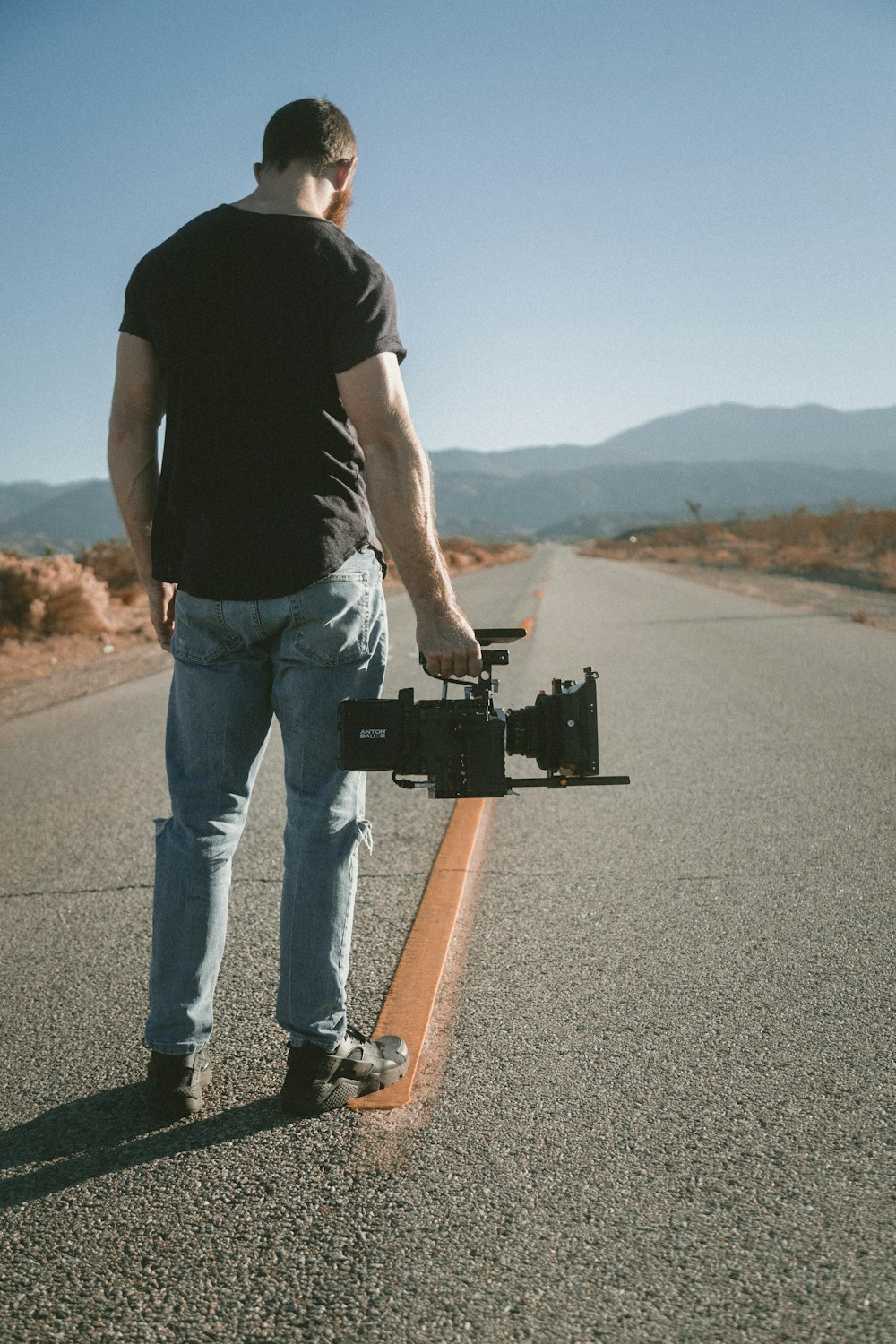 man holding video camera sanding on road