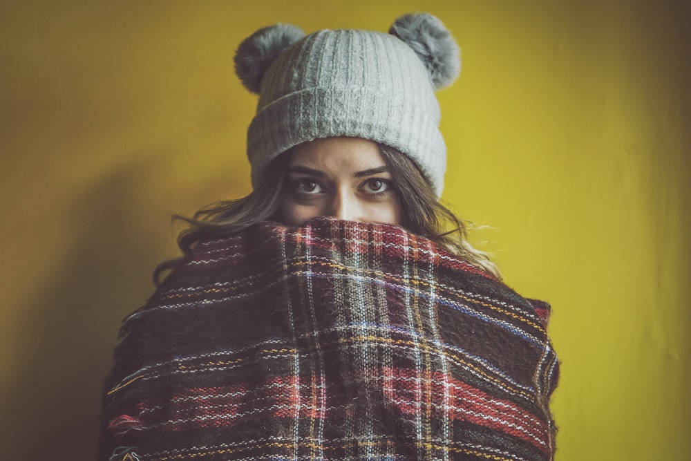 woman wearing hat and covering her face of cloth