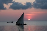 photograph of sail boat on calm body of water during golden hour