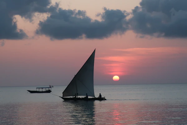 Traditional wooden dhow sailing on the Indian Ocean at golden sunset