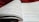 An open book with pages filled with mathematical formulas and text. The writing includes complex equations and mathematical symbols spread across two facing pages. The background is soft and out of focus, with what appears to be a red fabric.