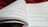 An open book with pages filled with mathematical formulas and text. The writing includes complex equations and mathematical symbols spread across two facing pages. The background is soft and out of focus, with what appears to be a red fabric.