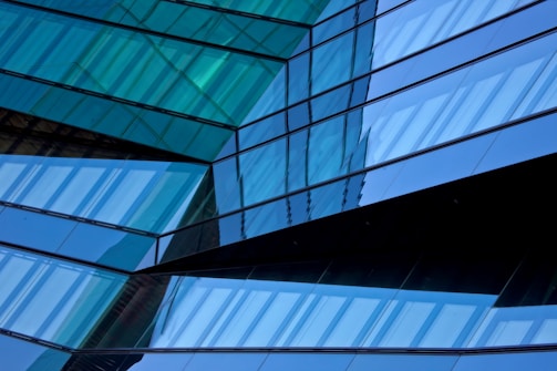 Modern glass building reflecting digital network patterns in teal and blue