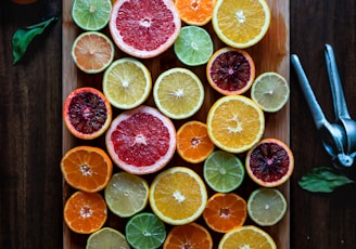 assorted sliced citrus fruits on brown wooden chopping board