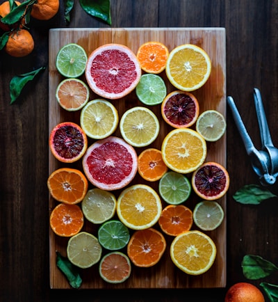 assorted sliced citrus fruits on brown wooden chopping board