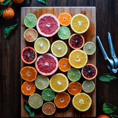 assorted sliced citrus fruits on brown wooden chopping board