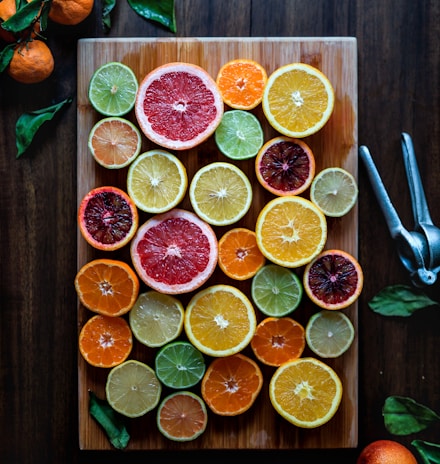 assorted sliced citrus fruits on brown wooden chopping board