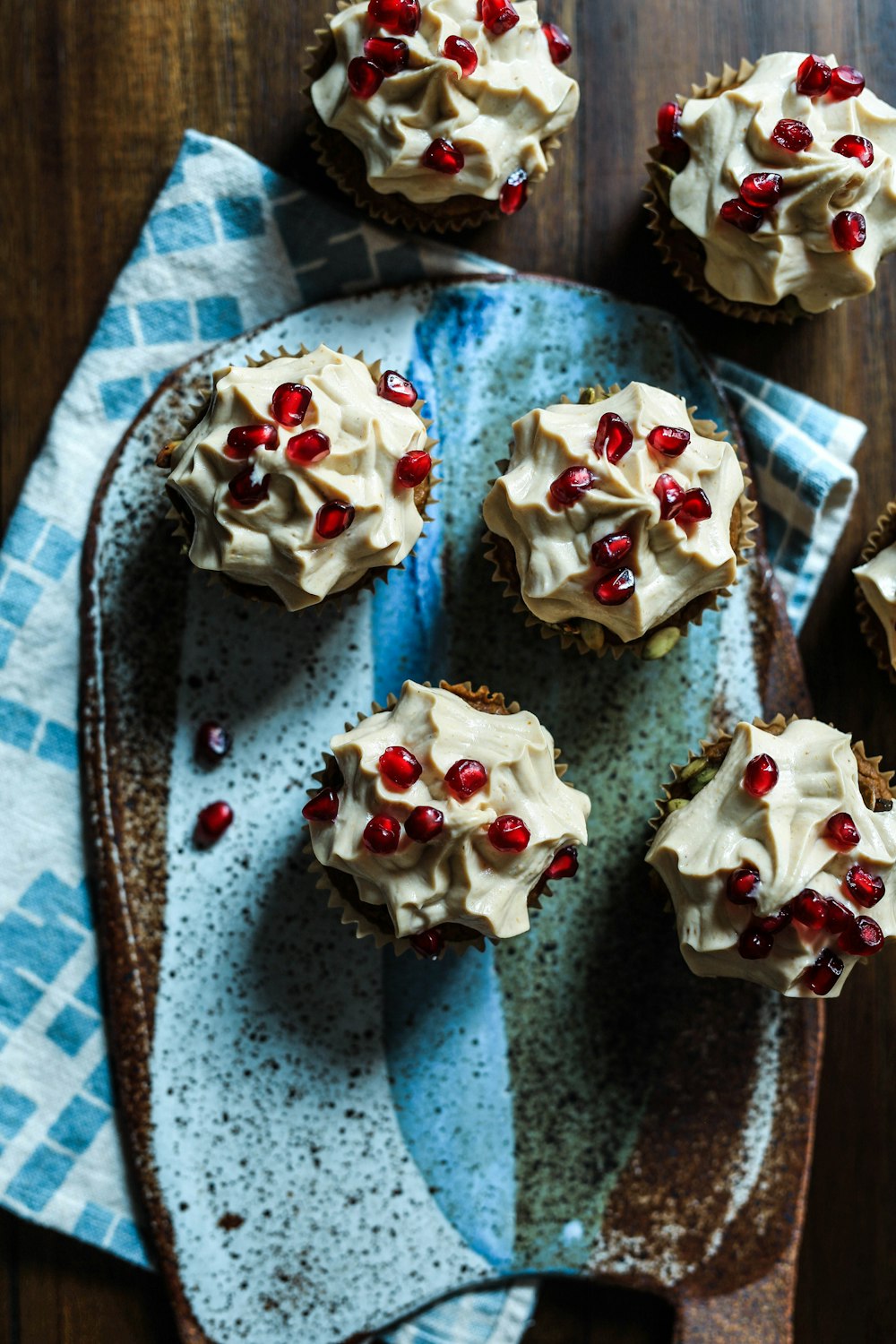 vários muffins cobertos com creme e sementes de romã