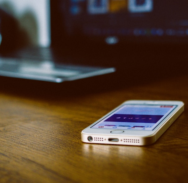 silver iPhone 5s on brown wooden desk