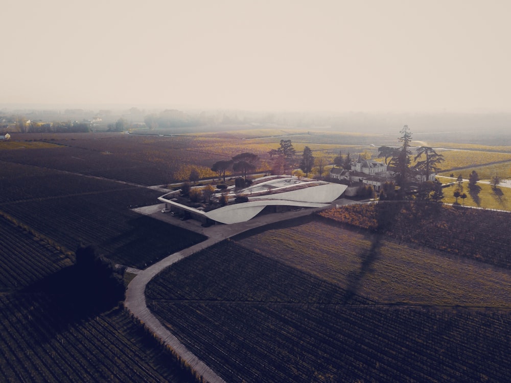 gray concrete building surrounded with green fields during cloudy day