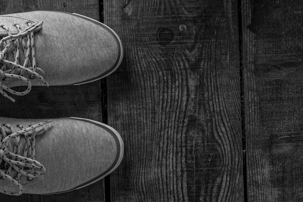 A pair of trendy sneakers positioned on a rustic floor with warm tones.