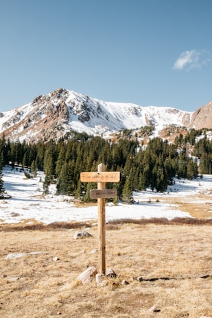 wooden signage stand on the ground and view of snow mountain