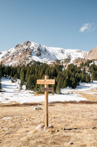 wooden signage stand on the ground and view of snow mountain