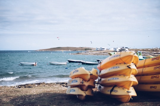 yellow row boat lot on seashore in distance white and black boats on body of water under white sky at daytime in Premantura Croatia