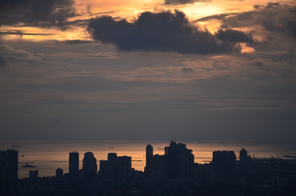 silhouette of buildings under gray clouds during golden hour