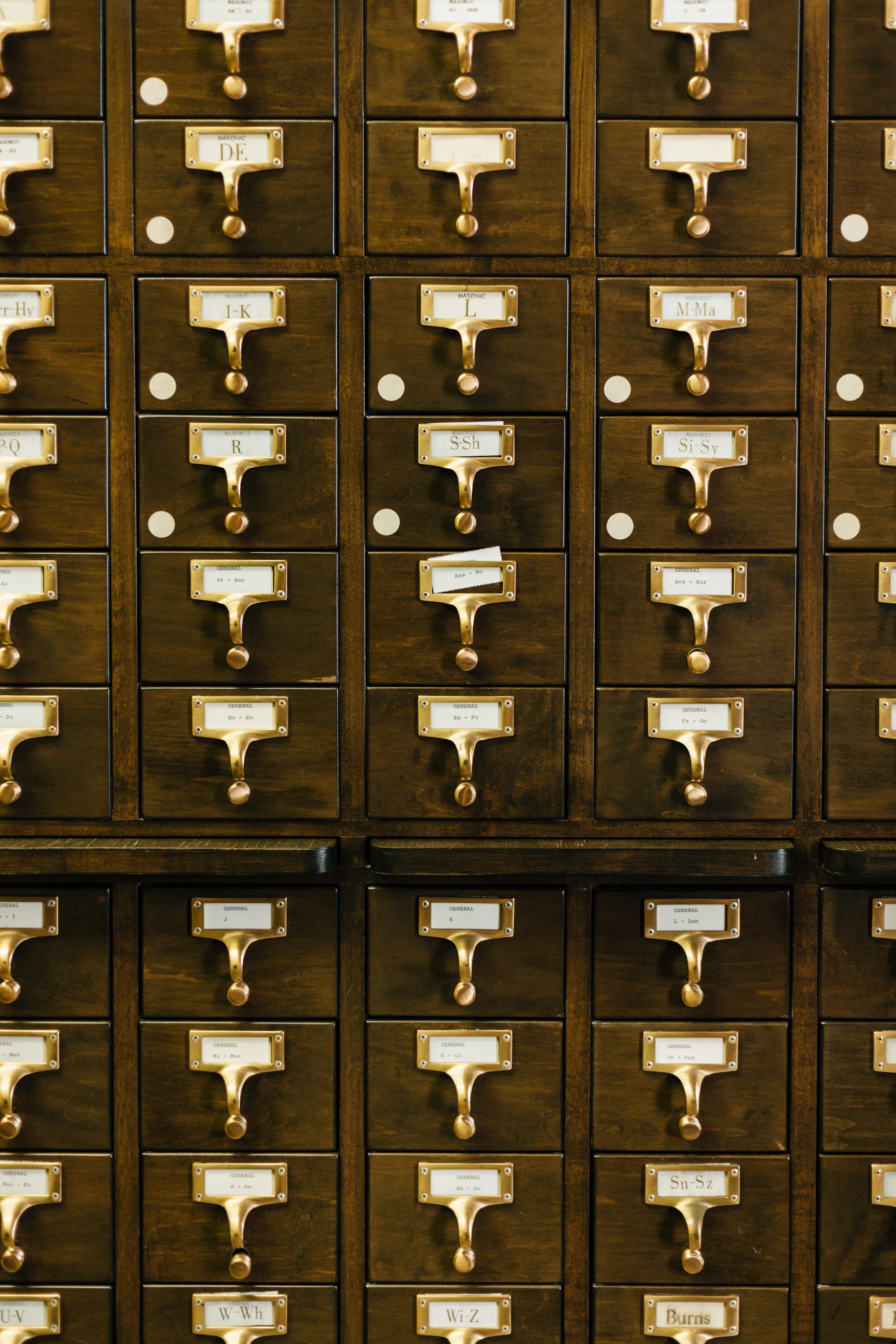 Rows of wooden library card catalogue drawers with brass label holders
