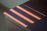 Sunlight casting warm shadows over a set of bright, hand-painted plates on a wooden table.