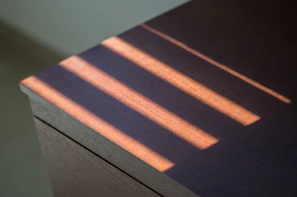 Sunlight casting warm shadows over a set of bright, hand-painted plates on a wooden table.