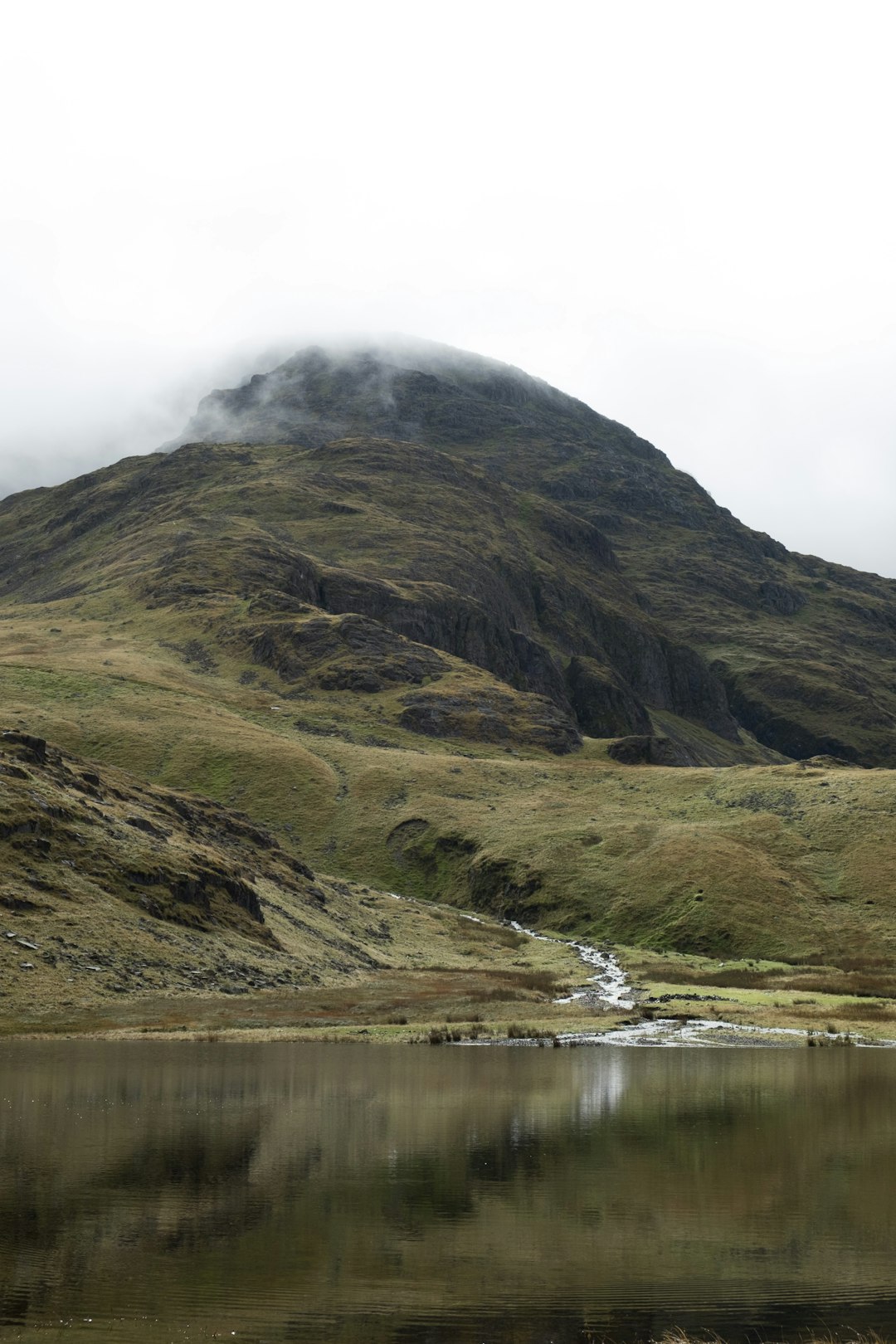 calm body of water and mountain covered with fogs