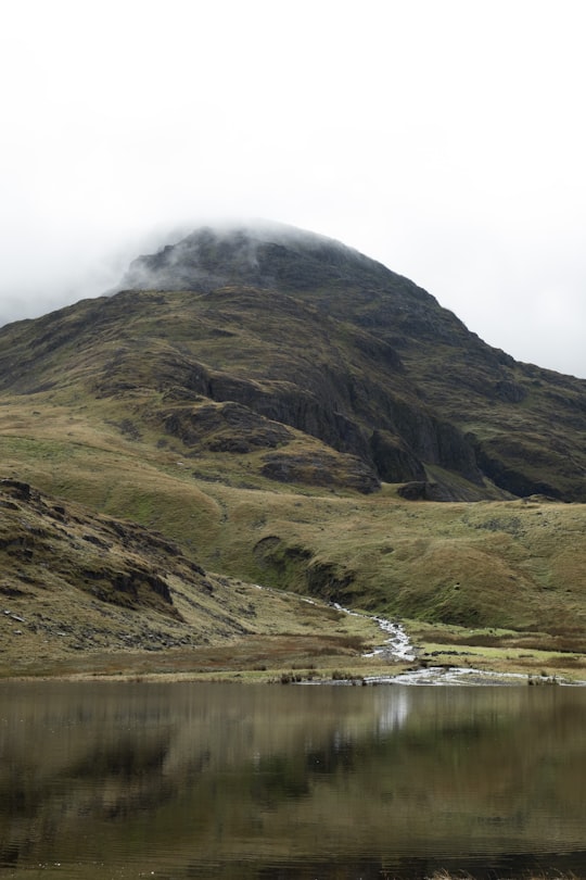 calm body of water and mountain covered with fogs in Sprinkling Tarn United Kingdom