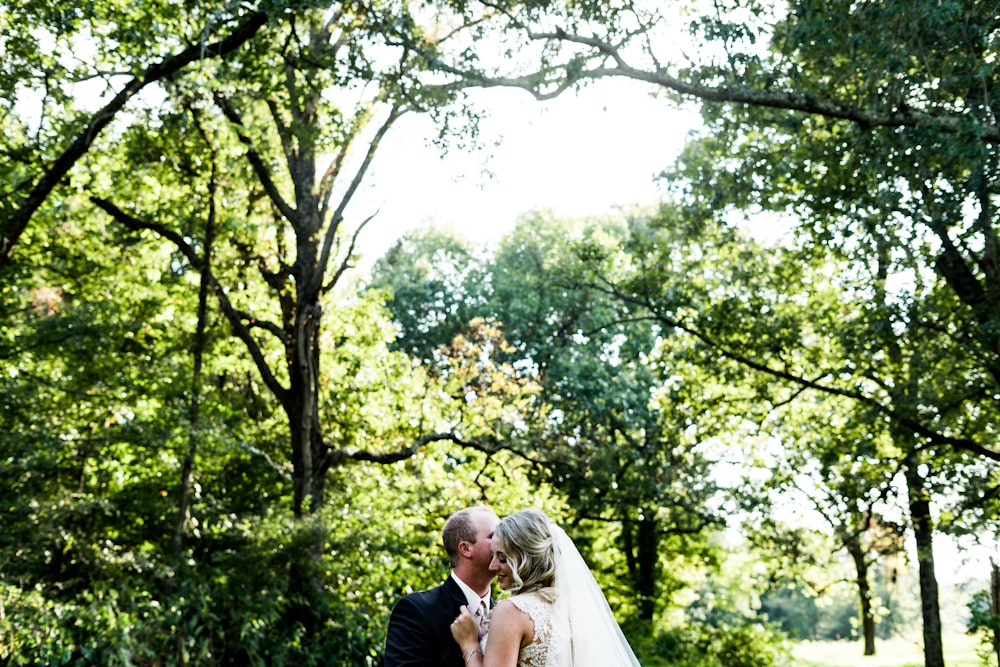 a bride and groom kissing in a park