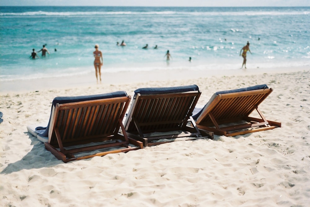 Drei Liegestühle am Meer in der Nähe einer Frau im Bikini