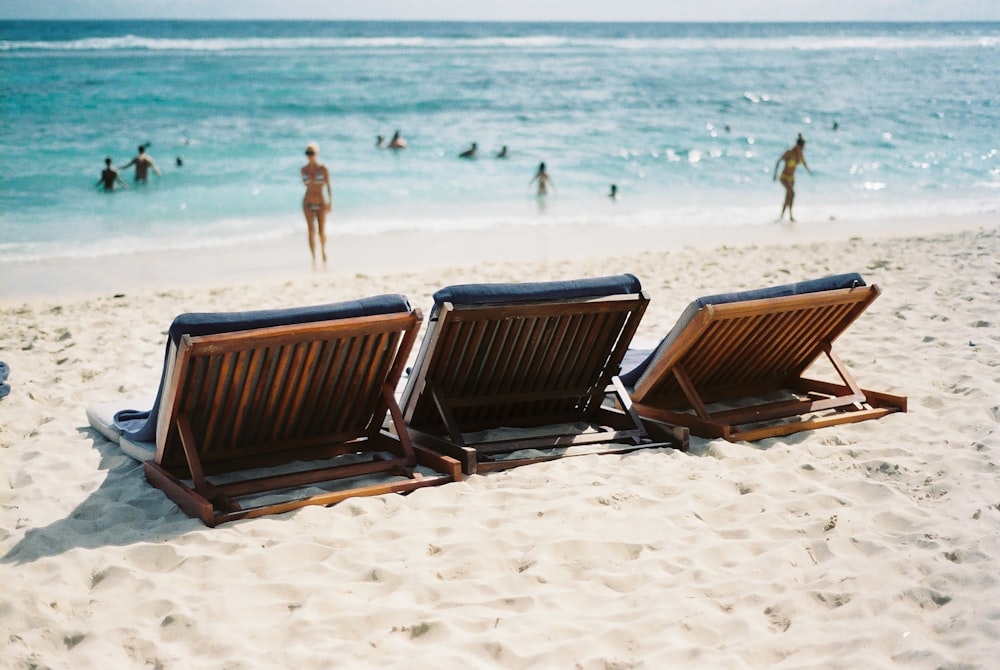 비키니를 입은 여자 근처 해변에 있는 3개의 일광욕 의자