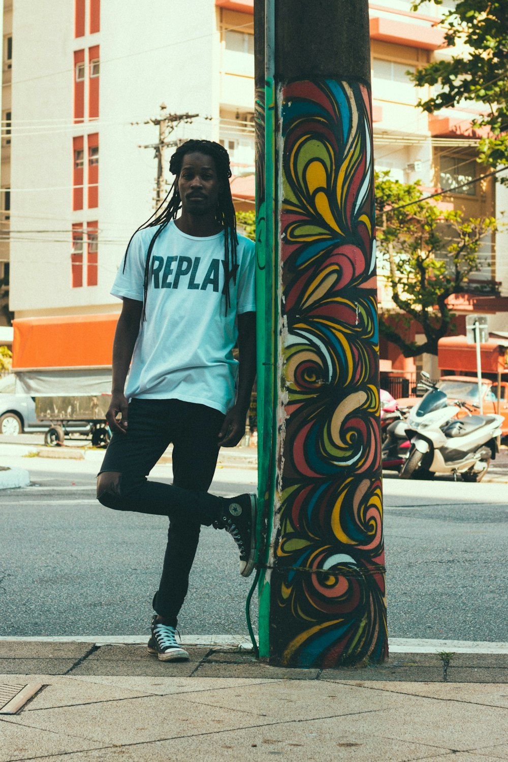 man standing leaning against green concrete post