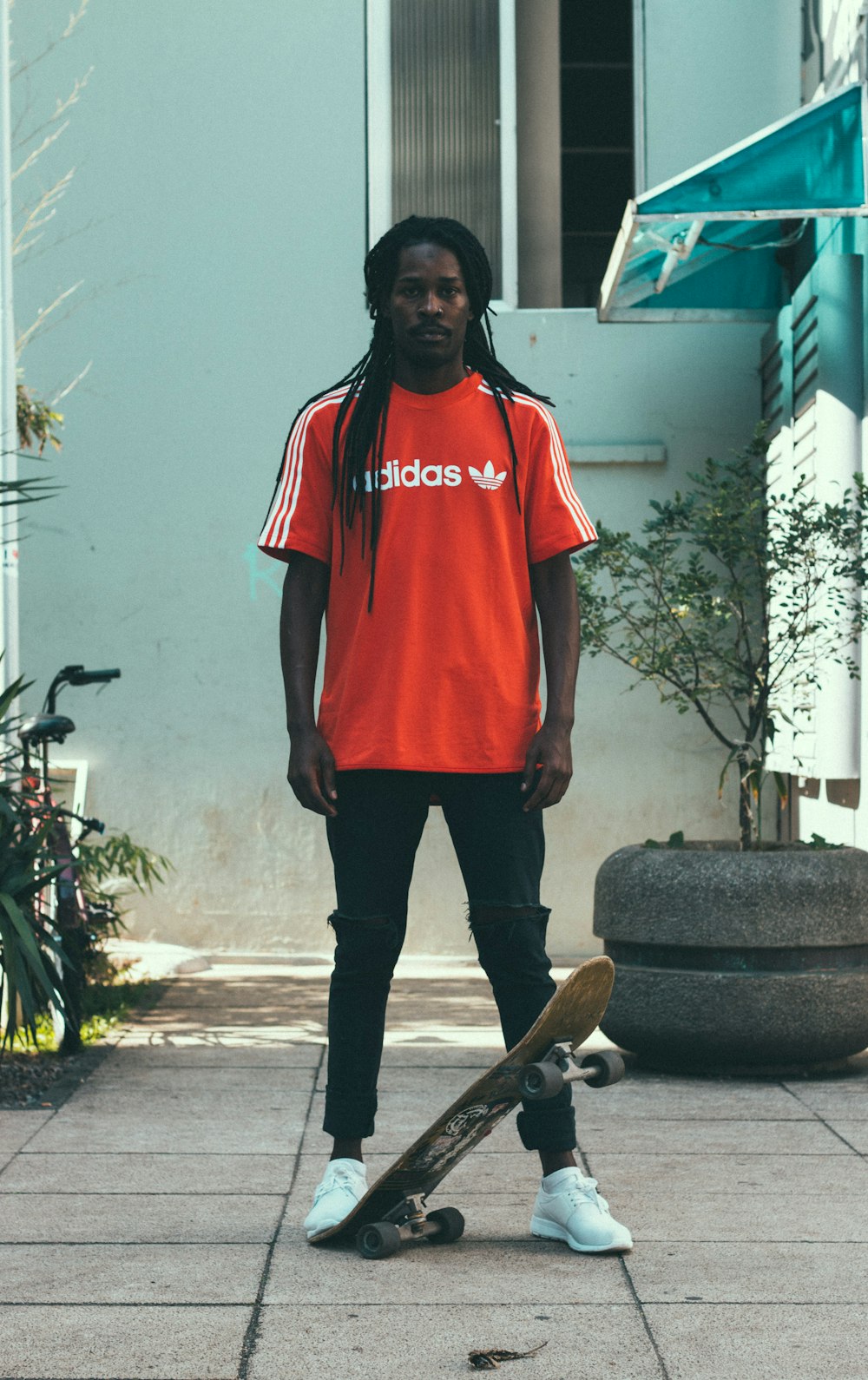 man standing near gray garden pot with skateboard