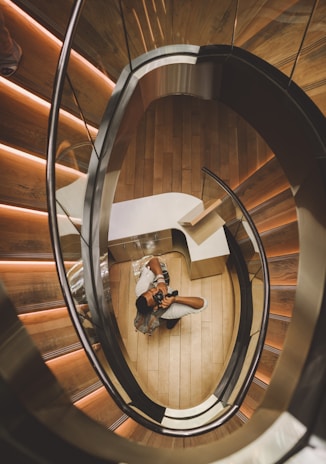 aerial photography of man holding camera taking picture under spiral stair