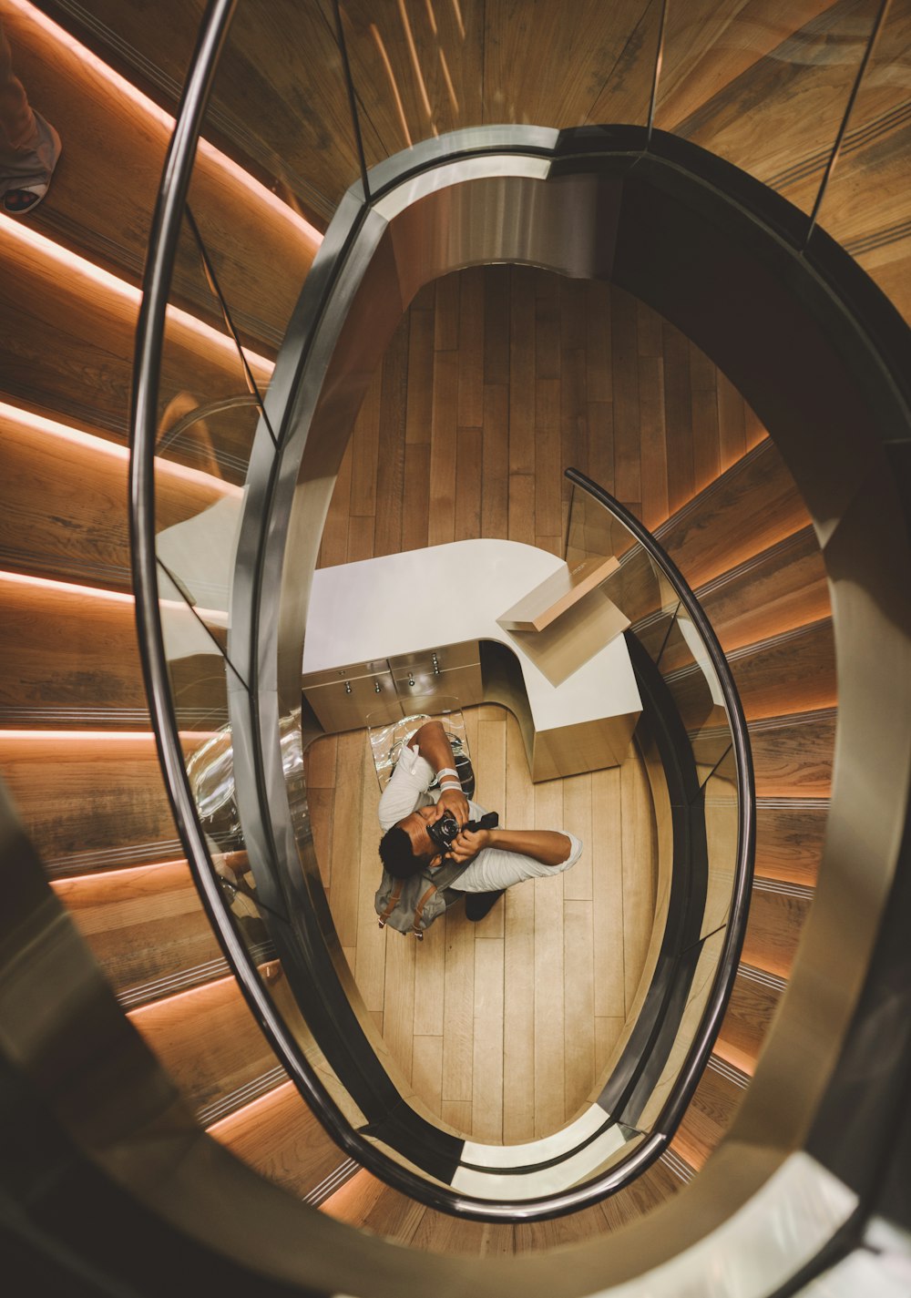 aerial photography of man holding camera taking picture under spiral stair