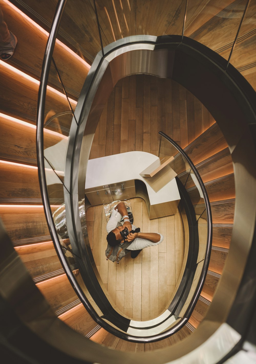 Luftaufnahme eines Mannes mit Kamera, der unter einer Wendeltreppe fotografiert