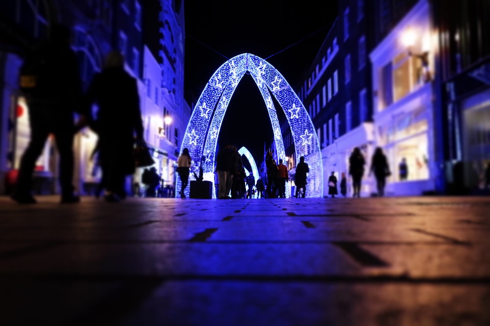 people walking near arched lighted decor between buildings