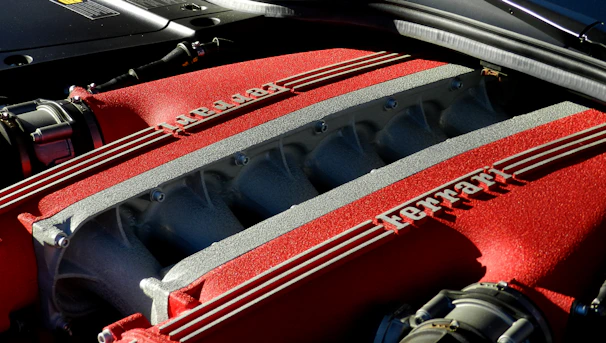 Close-up of a gleaming red Ferrari engine part resting on a sleek black workbench.