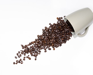 coffee beans beside gray ceramic mug