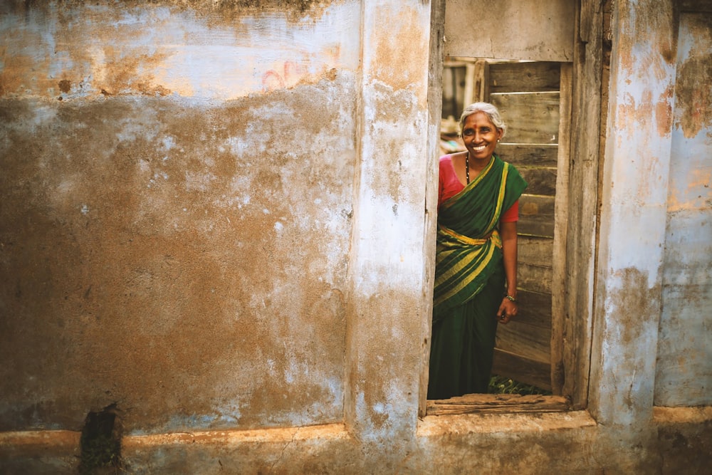 smiling woman wearing sari standing near door