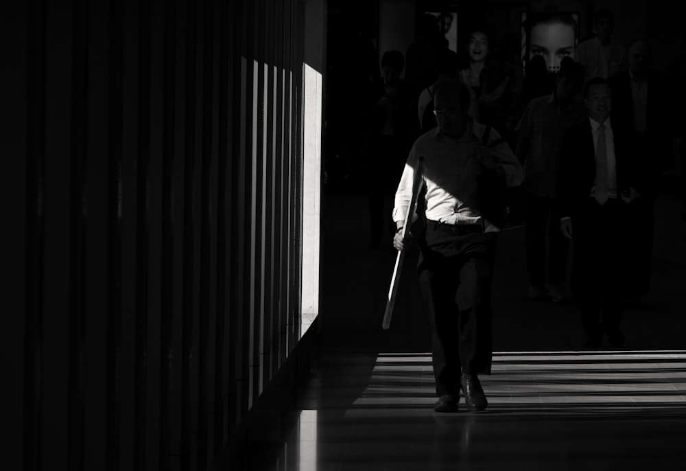 grayscale photography of man waking in the hall