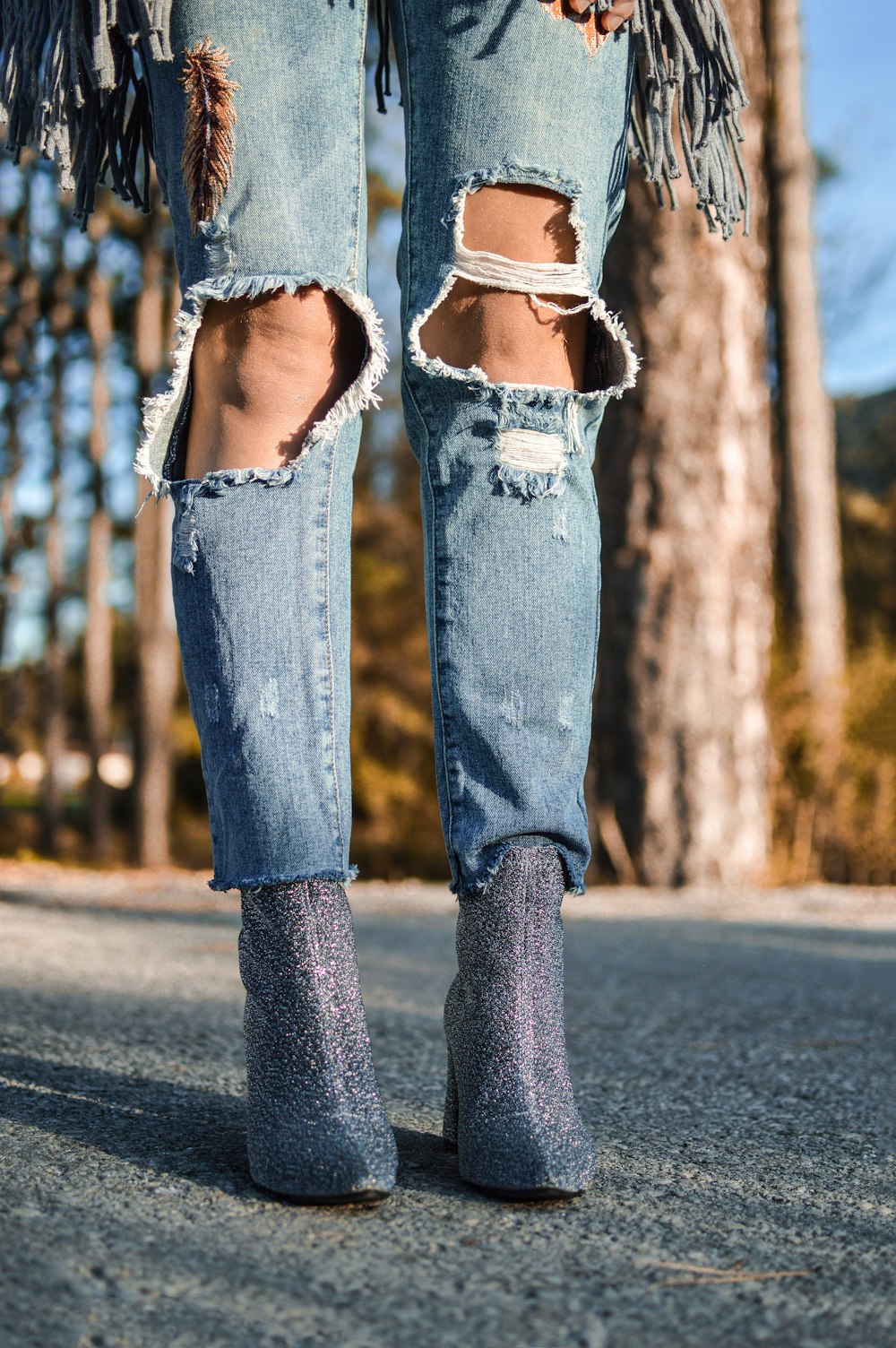 woman wearing distressed blue denim jeans and pair of purple glitter booties