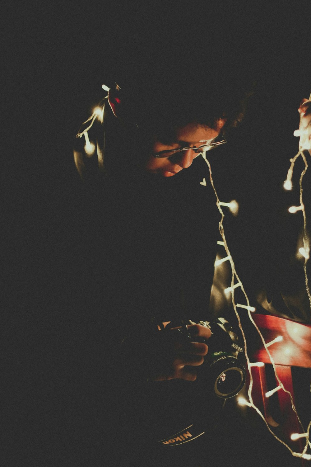 man holding DSLR camera with string light backdrop