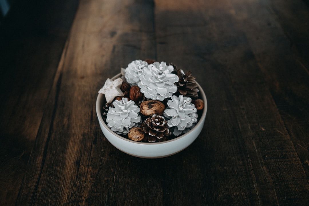 silver and black pinecone decor in white bowl on table