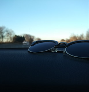 Close-up of sleek polarized sunglasses resting on a car dashboard with sunlight reflecting off the lenses.