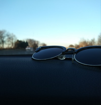 Close-up of sleek polarized sunglasses resting on a car dashboard with sunlight reflecting off the lenses.