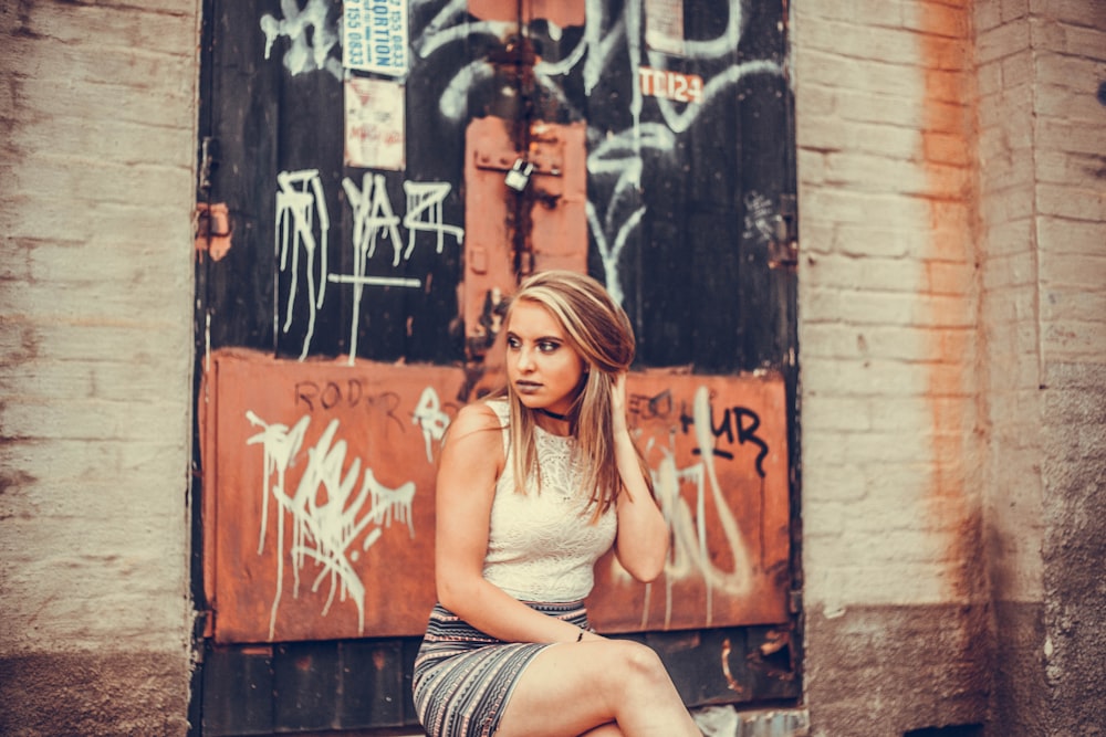 Femme assise sur un banc en béton touchant ses cheveux blonds