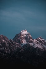 Cinematic 4K image of a snow-capped mountain peak bathed in twilight with deep blue ice below.