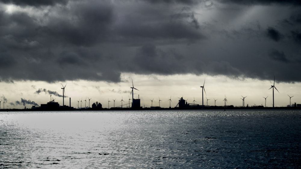silhouette of wind turbines under cloudy sky