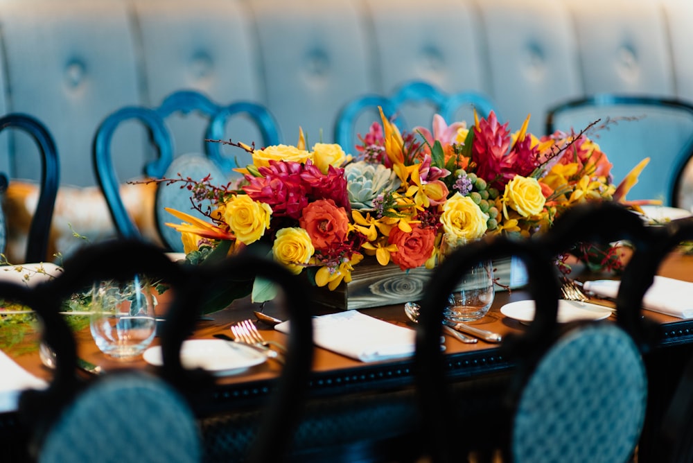 fiori rossi e gialli su tavolo da pranzo in legno marrone