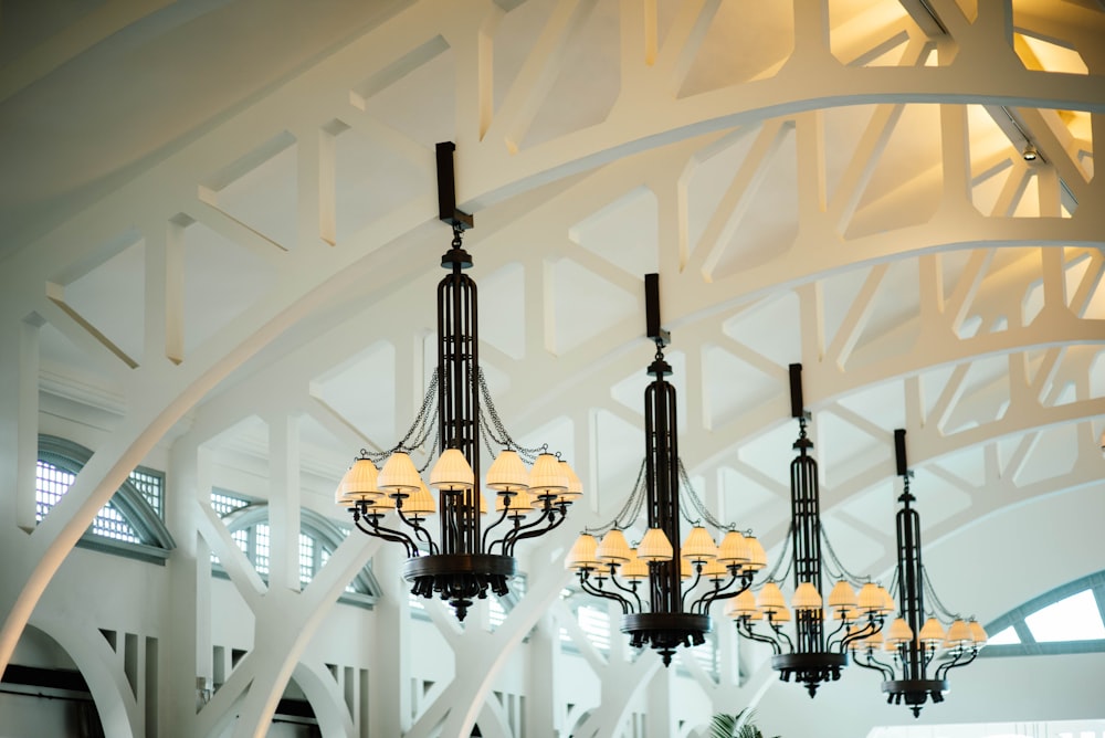 four black-and-white chandeliers inlined hang in white ceiling