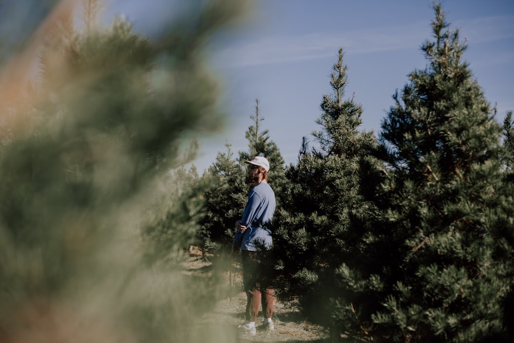 man standing near pine trees