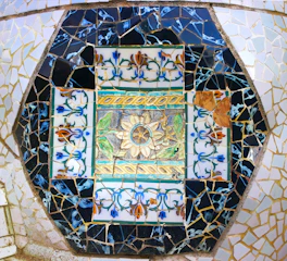 A colorful mosaic made from broken ceramic shards arranged into a flower pattern.