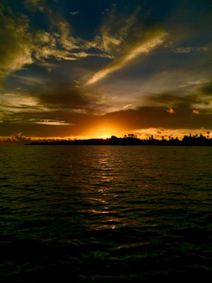 A stunning sunset over a pristine Malaysian beach with golden hues reflecting on calm waters.